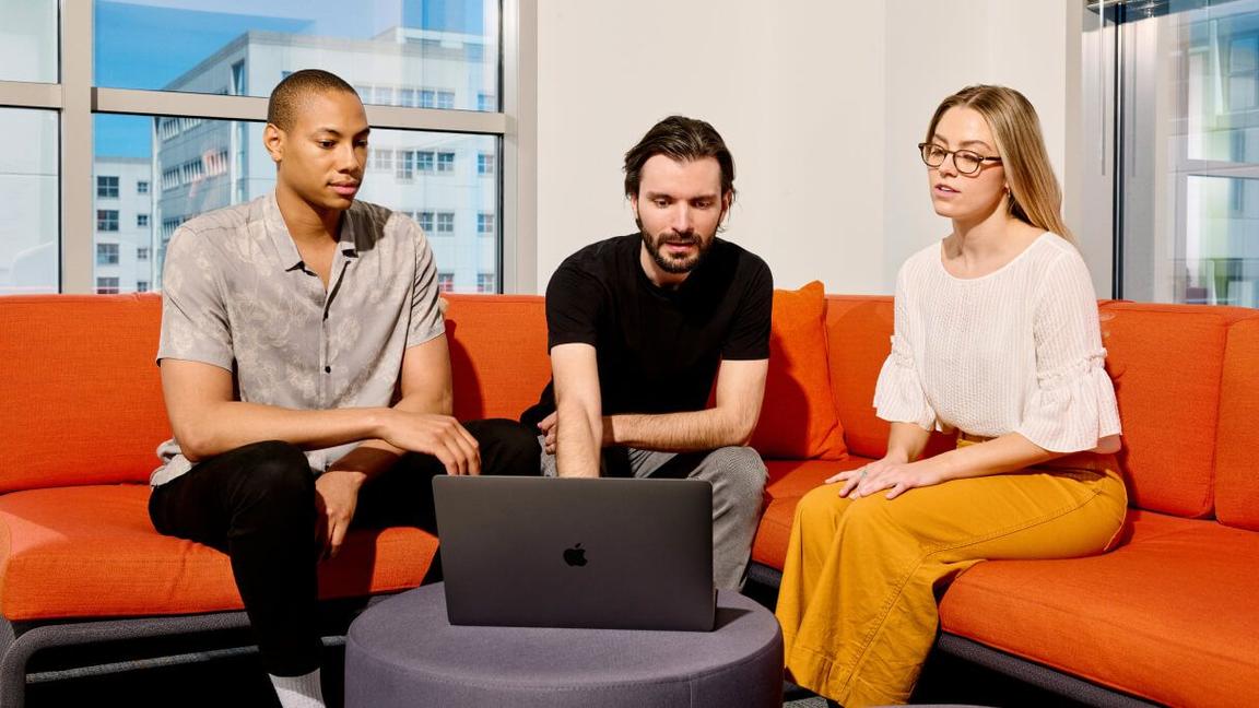 three colleagues on casual seating viewing laptop three colleagues on casual seating viewing laptop