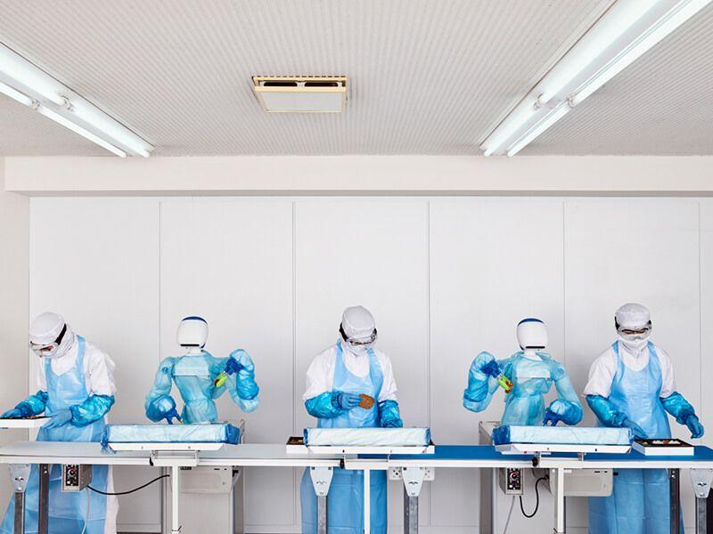 humans in clean room garments preparing food alongside robots in factory humans in clean room garments preparing food alongside robots in factory